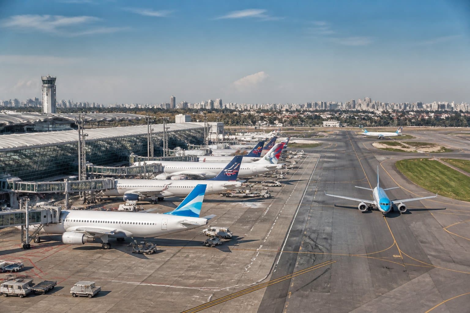 Vista panorâmica dos principais aeroportos comerciais de Buenos Aires com terminais modernos, aviões nas pistas e veículos de serviço em operação.